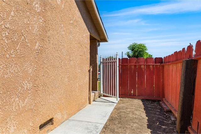 view of property exterior featuring a gate, stucco siding, and fence