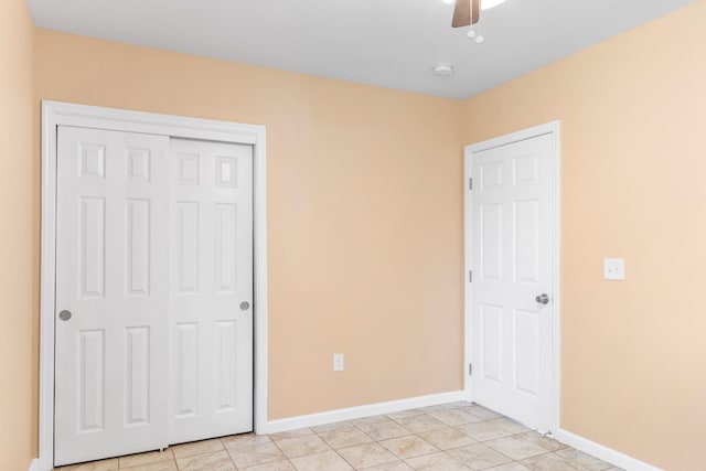 unfurnished bedroom with light tile patterned floors, baseboards, a ceiling fan, and a closet