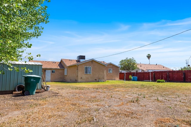 rear view of property featuring fence, a yard, stucco siding, and cooling unit