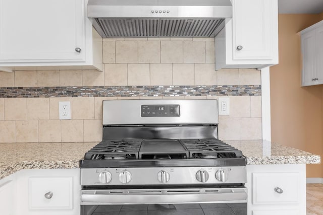 kitchen with backsplash, white cabinets, stainless steel gas range oven, and wall chimney exhaust hood