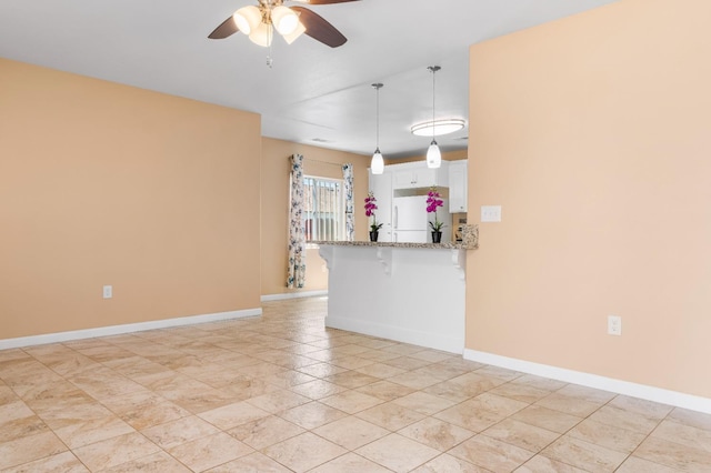 unfurnished living room featuring ceiling fan and baseboards