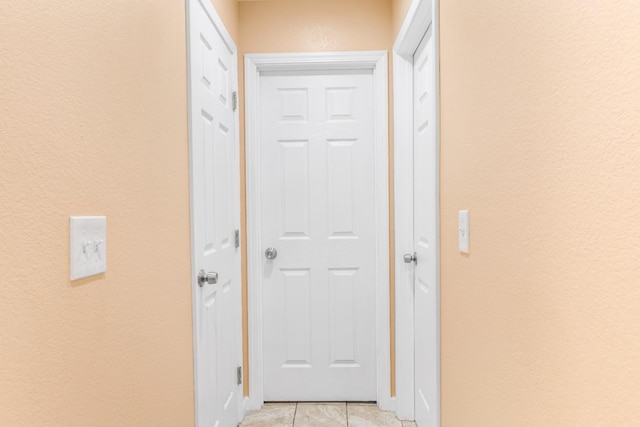 hall featuring a textured wall and light tile patterned flooring