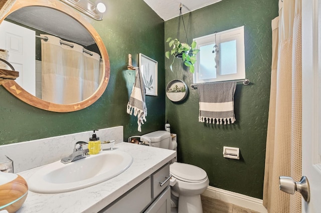 full bath with toilet, a textured wall, wood finished floors, and vanity