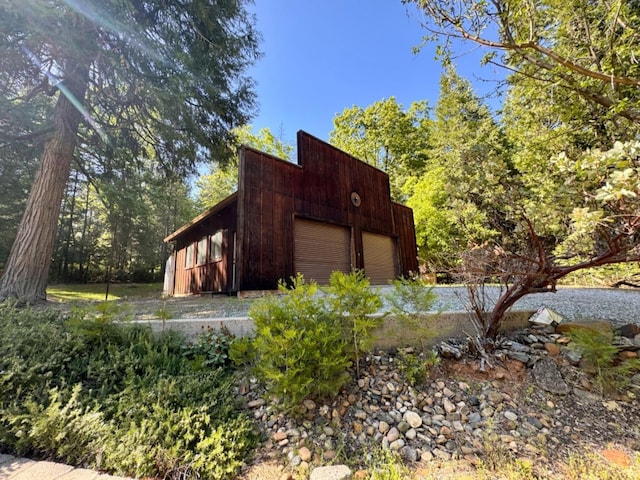 view of side of home featuring a garage and an outbuilding