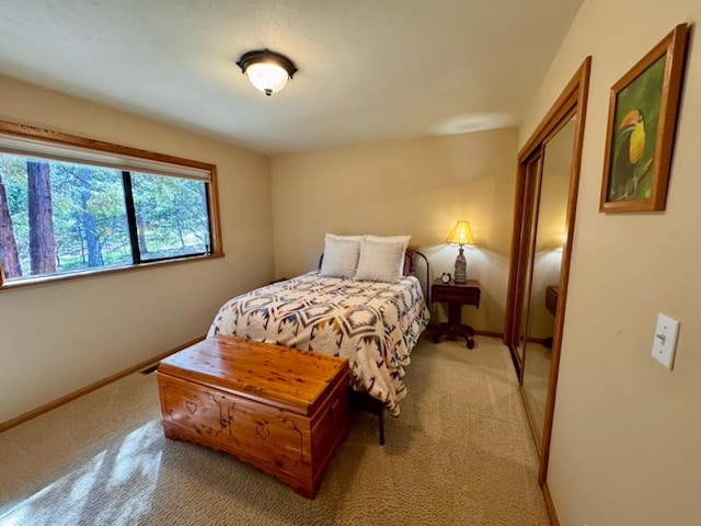 bedroom with a closet, baseboards, and light carpet