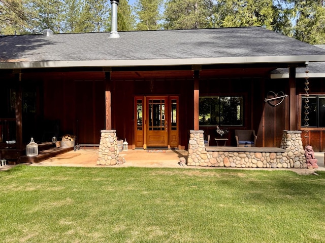 back of property with a lawn and a shingled roof