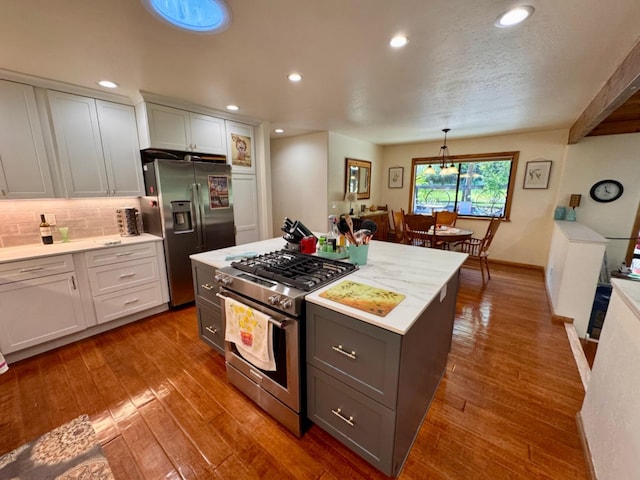 kitchen with gray cabinets, appliances with stainless steel finishes, tasteful backsplash, recessed lighting, and hardwood / wood-style floors
