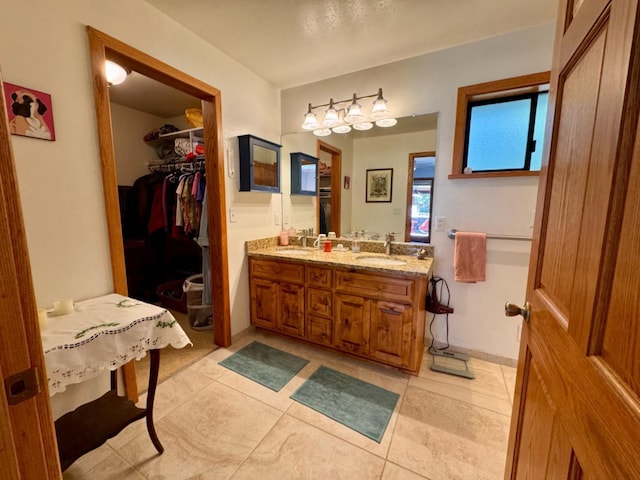 full bathroom with a sink, tile patterned floors, double vanity, and a spacious closet