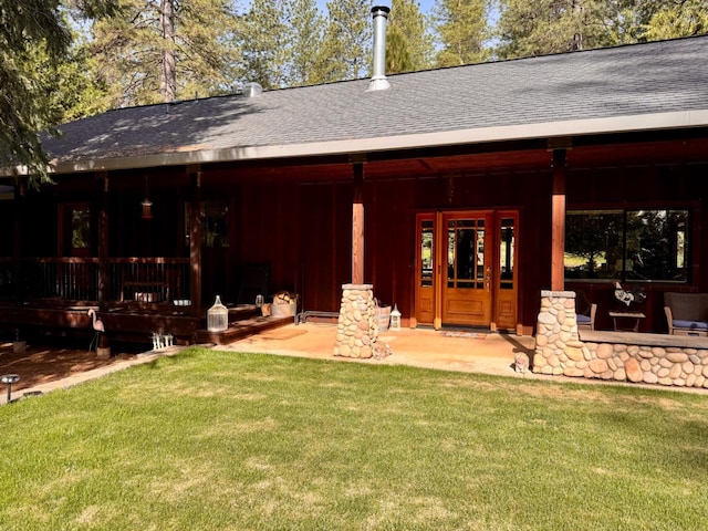 back of house featuring a lawn and a shingled roof