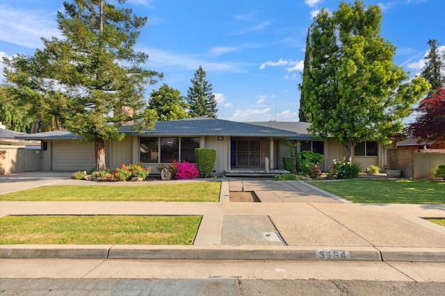 ranch-style home with a garage, board and batten siding, a front yard, and concrete driveway