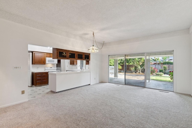unfurnished living room featuring baseboards, plenty of natural light, light carpet, and a chandelier
