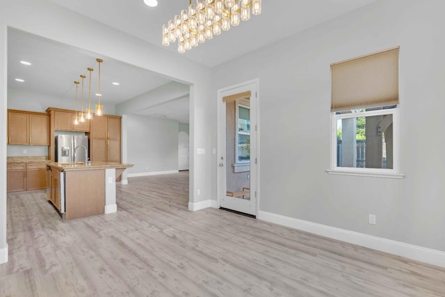 kitchen with light countertops, baseboards, stainless steel fridge with ice dispenser, light wood finished floors, and open floor plan