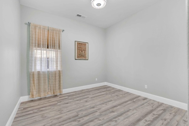 empty room with visible vents, baseboards, and wood finished floors