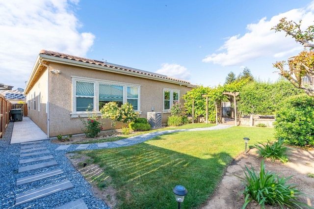 back of property featuring a yard, fence, and stucco siding