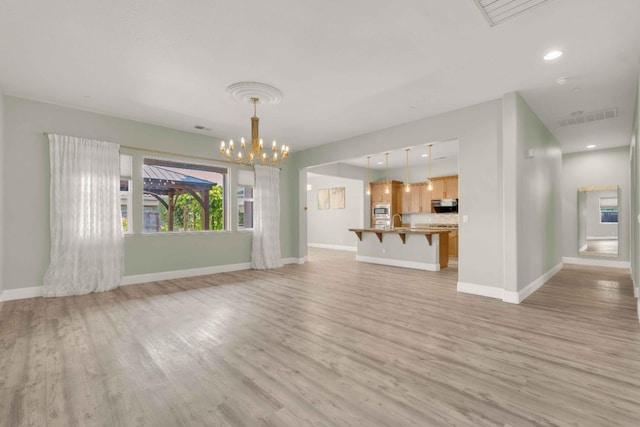 unfurnished living room with visible vents, baseboards, an inviting chandelier, and light wood finished floors