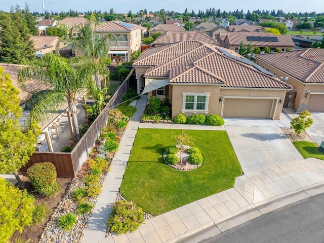 mediterranean / spanish-style house featuring fence, a residential view, a garage, stucco siding, and driveway