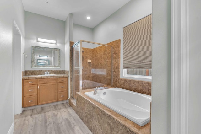 bathroom featuring a garden tub, wood finished floors, a stall shower, and vanity
