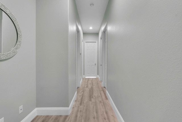 corridor with light wood-type flooring, recessed lighting, and baseboards