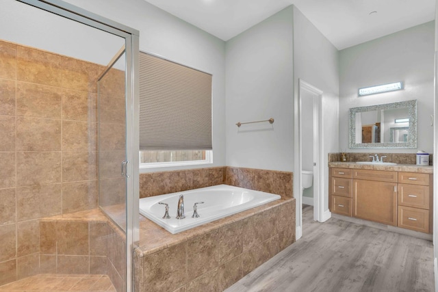 full bath featuring a bath, a shower stall, wood finished floors, vanity, and toilet