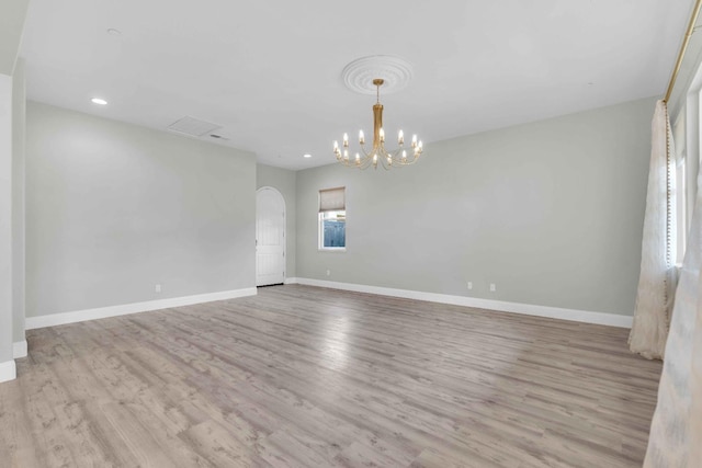 unfurnished room featuring arched walkways, baseboards, a notable chandelier, and wood finished floors