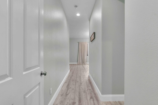 corridor featuring recessed lighting, baseboards, and light wood finished floors