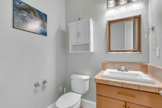bathroom featuring vanity, baseboards, and toilet