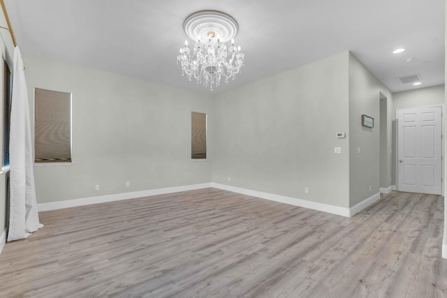 spare room featuring visible vents, wood finished floors, baseboards, a notable chandelier, and recessed lighting