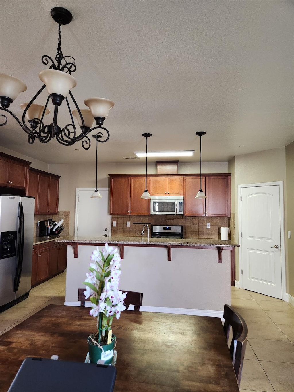 1439 De Ann Cv, Madera, CA 93637 - unfurnished dining area featuring light tile patterned floors, baseboards, an inviting chandelier, and a sink
