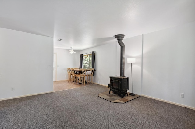 carpeted living room featuring ceiling fan, a wood stove, and visible vents