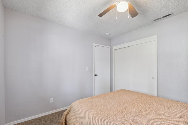 carpeted bedroom with baseboards, a closet, a textured ceiling, and visible vents