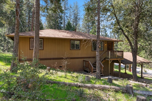 view of property exterior featuring stairs, roof with shingles, and a deck