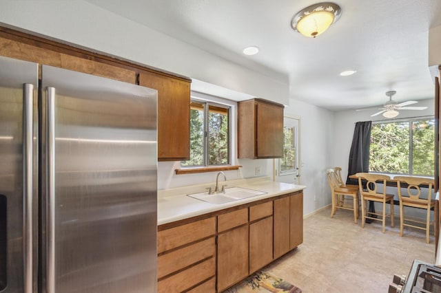 kitchen featuring freestanding refrigerator, a sink, a wealth of natural light, and light countertops