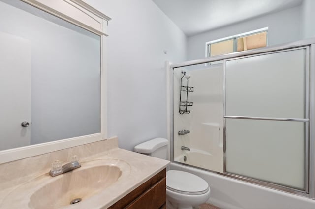 full bathroom featuring vanity, bath / shower combo with glass door, and toilet