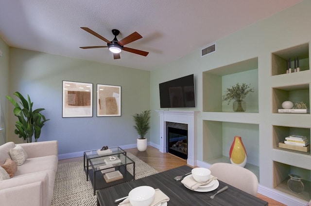 619 W Casanova Ln, Clovis, CA 93619 - living room with a ceiling fan, a glass covered fireplace, built in features, and wood finished floors
