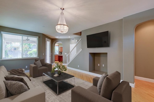 619 W Casanova Ln, Clovis, CA 93619 - living area featuring arched walkways, light wood finished floors, stairs, baseboards, and a chandelier