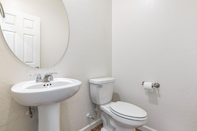 6260 E Malbec Dr, Fresno, CA 93727 - half bath featuring toilet, baseboards, a textured wall, and a sink