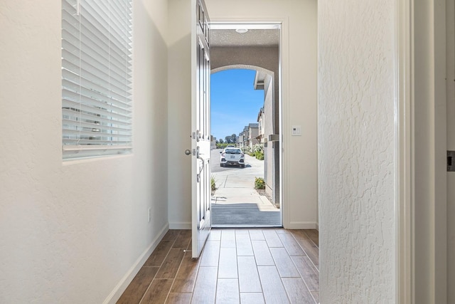 6260 E Malbec Dr, Fresno, CA 93727 - doorway with arched walkways, a textured wall, baseboards, and wood finished floors