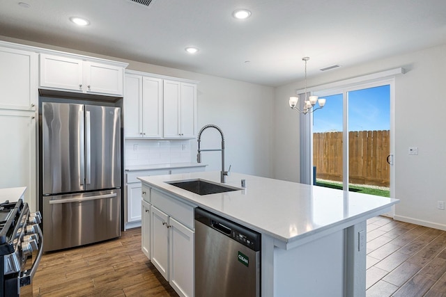 6260 E Malbec Dr, Fresno, CA 93727 - kitchen featuring wood finished floors, a chandelier, a sink, backsplash, and stainless steel appliances