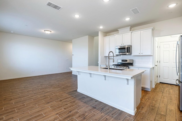 6260 E Malbec Dr, Fresno, CA 93727 - kitchen with visible vents, a kitchen island with sink, wood finished floors, a sink, and stainless steel appliances