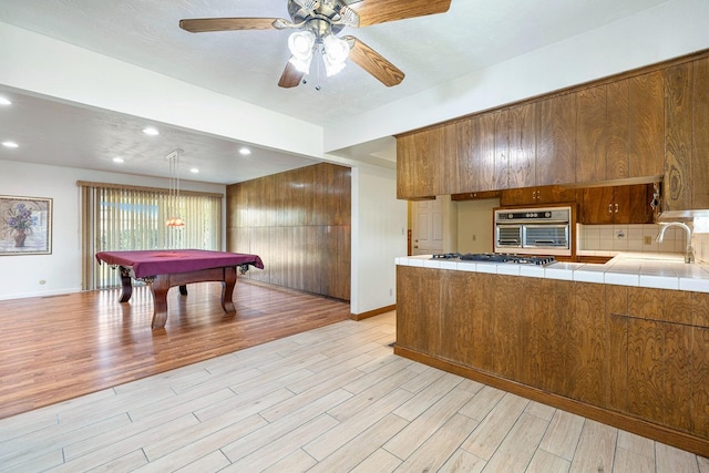 6154 E Alta Ave, Fresno, CA 93727 - kitchen featuring oven, tile counters, gas cooktop, brown cabinets, and a sink