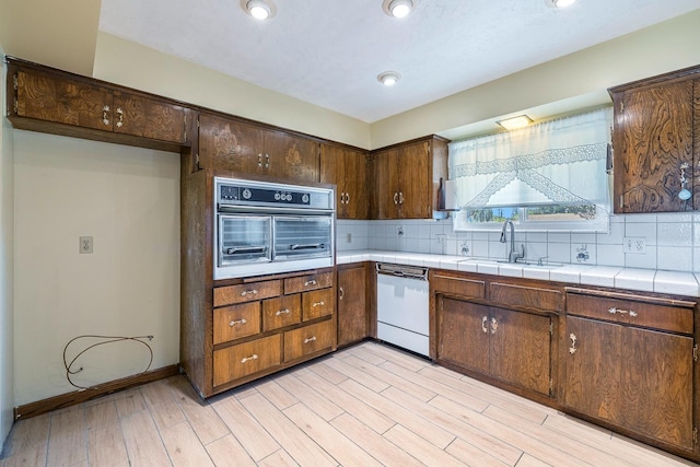6154 E Alta Ave, Fresno, CA 93727 - kitchen featuring white dishwasher, decorative backsplash, a sink, and oven
