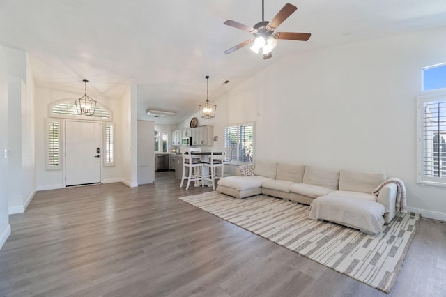 living area with baseboards, ceiling fan with notable chandelier, and wood finished floors