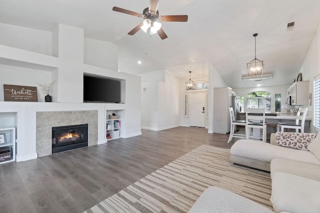living room featuring a fireplace, built in features, wood finished floors, lofted ceiling, and visible vents