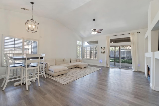 living room with baseboards, ceiling fan with notable chandelier, lofted ceiling, and a wealth of natural light