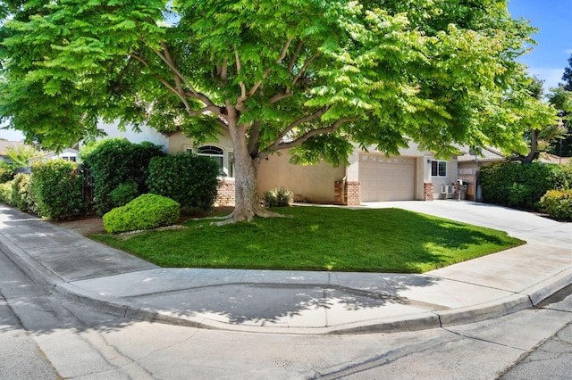 view of property hidden behind natural elements with a garage, a front yard, stucco siding, brick siding, and concrete driveway