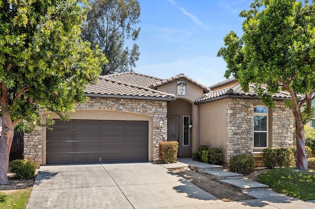 5534 N La Ventana Ave, Fresno, CA 93723 - mediterranean / spanish-style house with a garage, stucco siding, concrete driveway, and stone siding