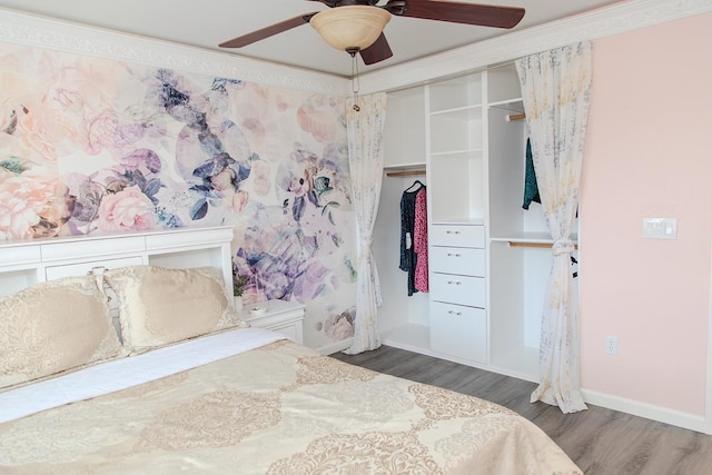 bedroom with crown molding, a closet, wood finished floors, baseboards, and ceiling fan