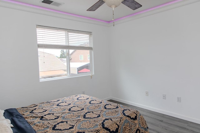 bedroom featuring visible vents, a ceiling fan, baseboards, and wood finished floors