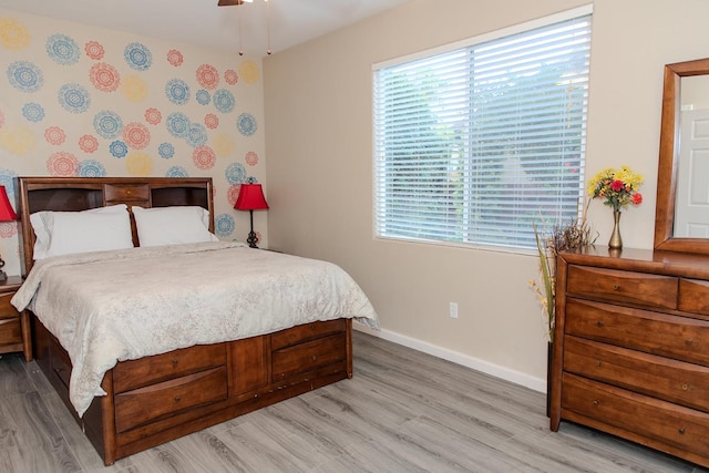bedroom with baseboards, wood finished floors, and multiple windows