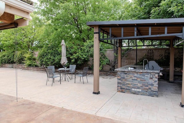 view of patio with fence, outdoor dining area, a gazebo, and exterior kitchen